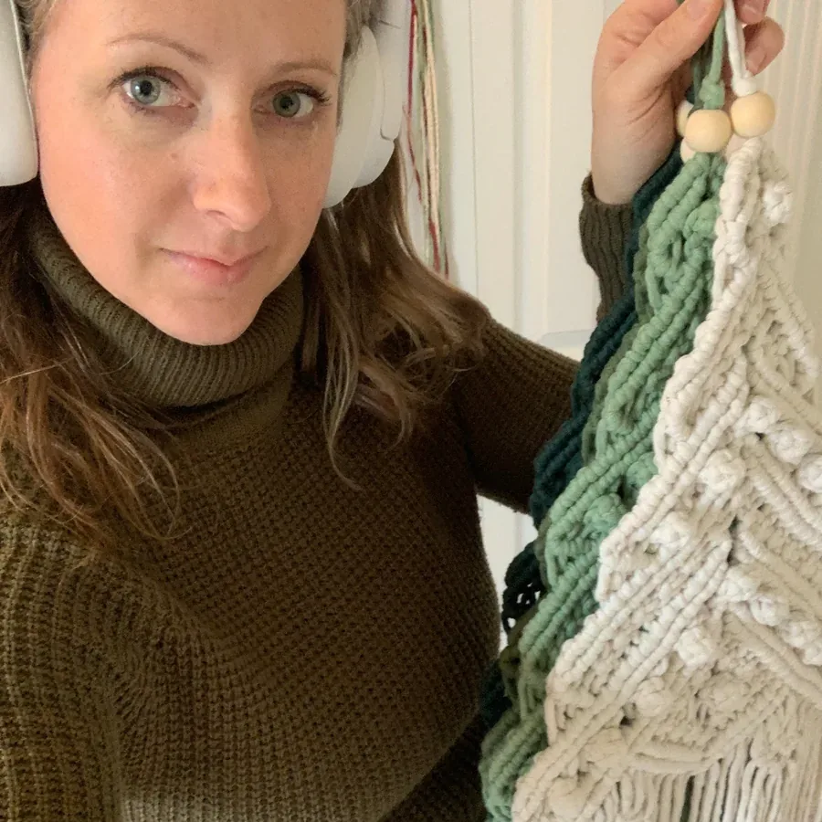 Sarah Boeker holding up one of her macramé wall hangings