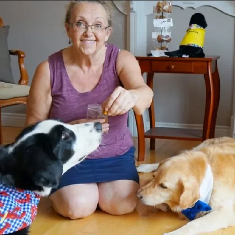 Renita Gallant giving treats to two dogs wearing Two Beggars bandanas